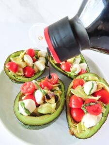 Pouring glaze over the finished Caprese Stuffed Avocado platter.