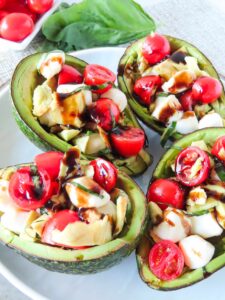 Several Caprese Stuffed Avocados on a white platter.