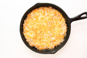 Melted cheese covers cheese burger dip in a cast iron skillet.