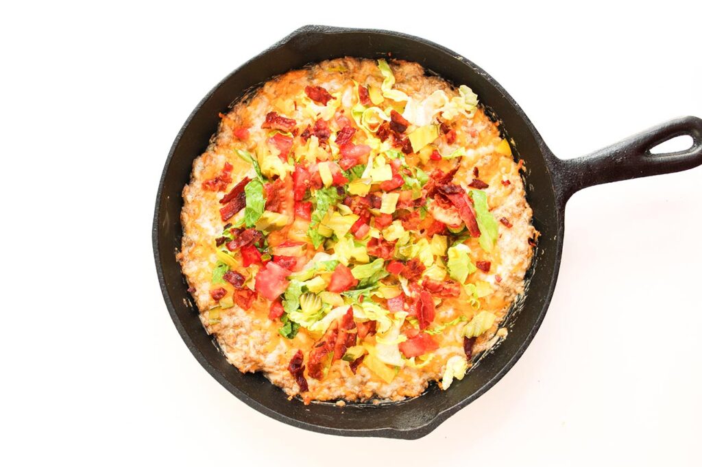 Lettuce, tomatoes, a chopped bacon added as toppings to cheese burger dip.