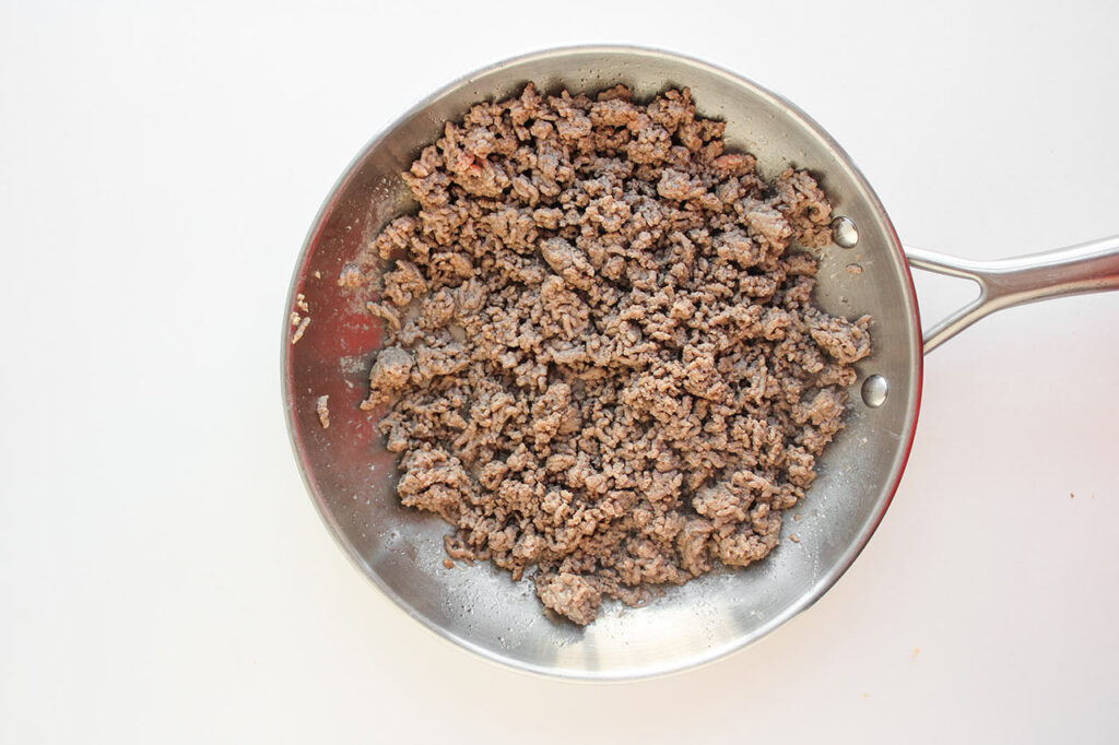 Cooked meat in a skillet for cheeseburger dip.