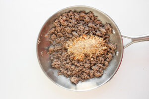 Onion spice mix added to ground meat in a skillet.