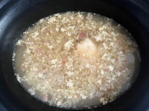 Cooked chicken in broth with onions. Overhead focus.