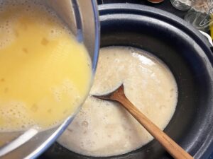 Adding tempered eggs into slow cooker crock with remaining soup.