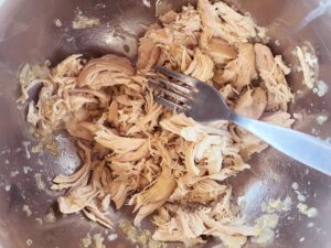 Shredded chicken in a bowl with a fork.