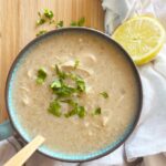 Overhead focus. A large mug of of Greek Avgolemono Soup on a wood surface.