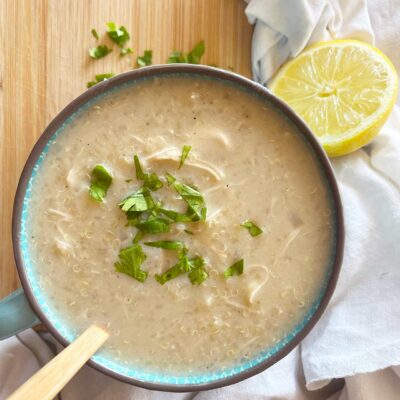 Overhead focus. A large mug of of Greek Avgolemono Soup on a wood surface.
