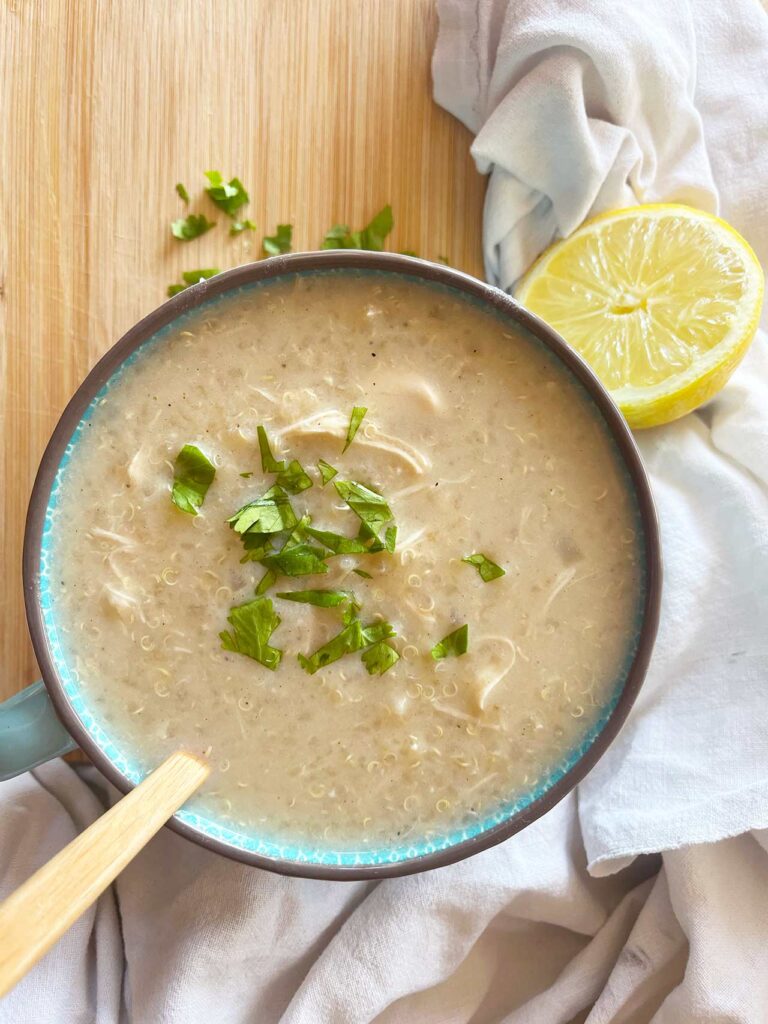 Overhead focus. A large mug of of Greek Avgolemono Soup on a wood surface.