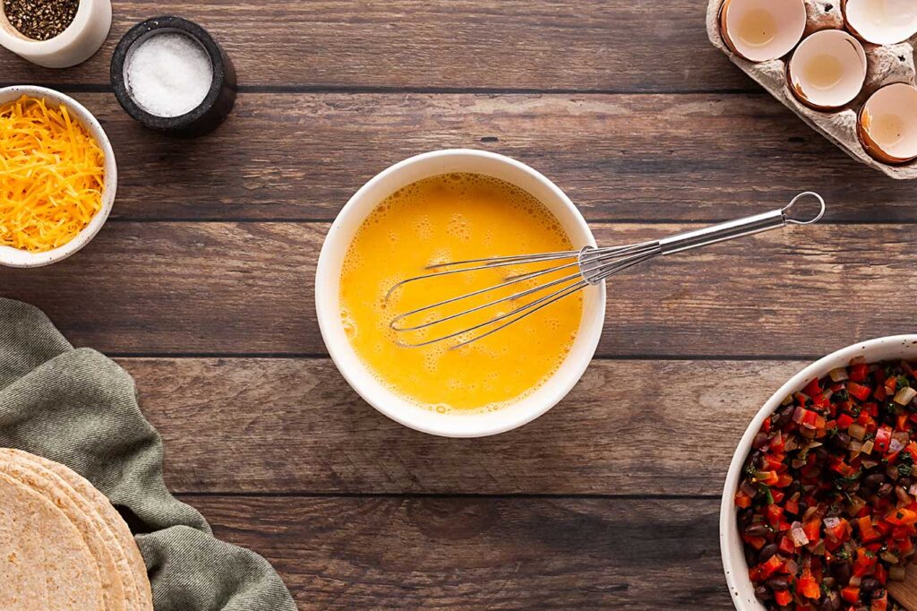 Whisked eggs in a bowl with a whisk.