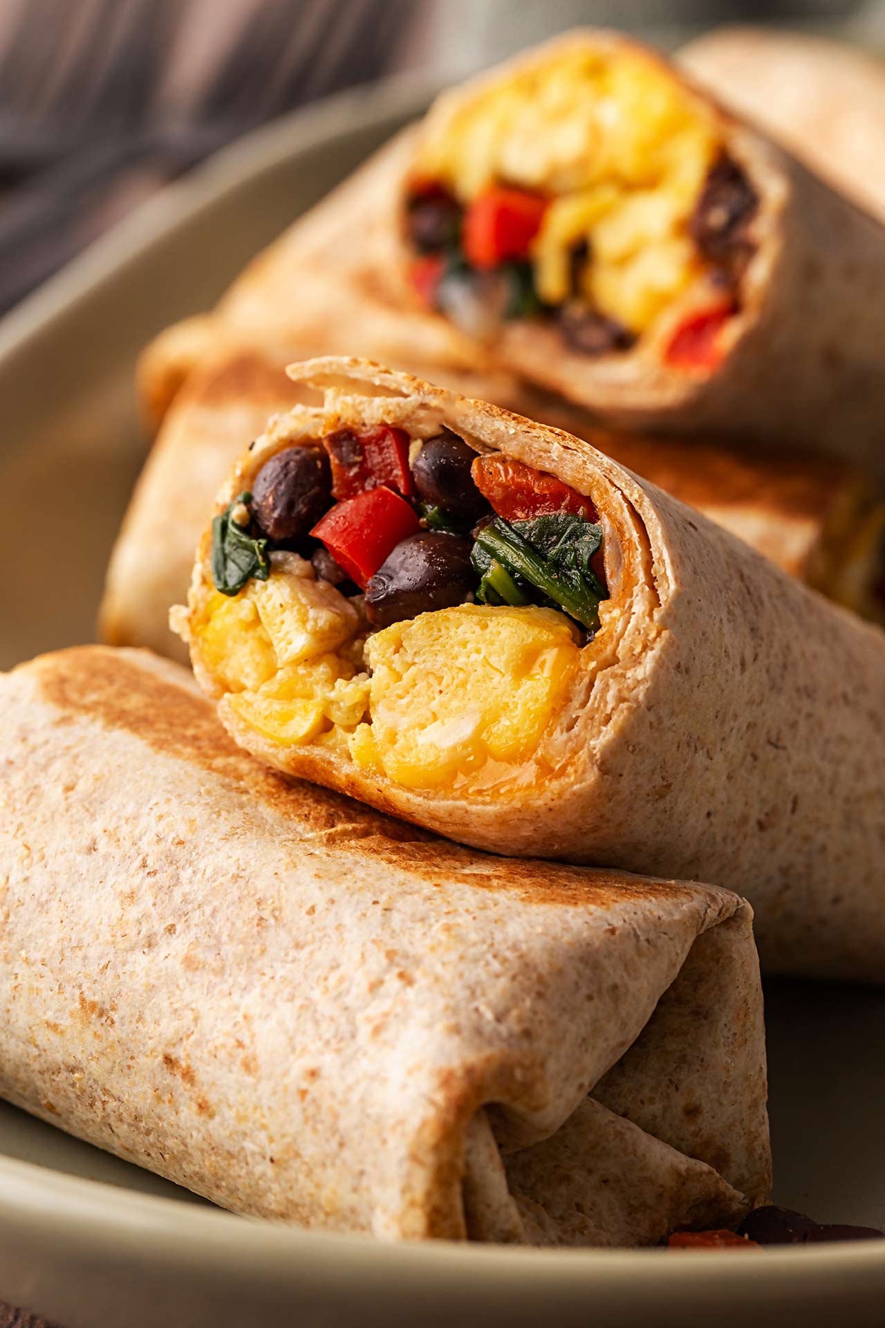 Healthy Breakfast Burritos on a platter with one cut open.