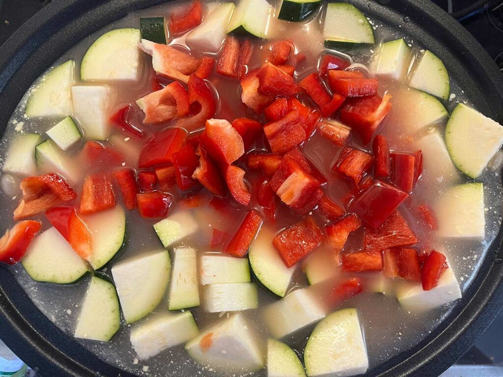 Chopped veggies added to a slow cooker crock.