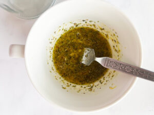 Mediterranean Detox Salad Jars salad dressing mixed in a white mug with a fork.