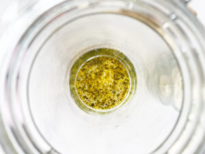 Dressing sitting in the bottom of a salad jar.