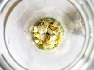 Onions and artichoke hearts added to the bottom of a salad jar.