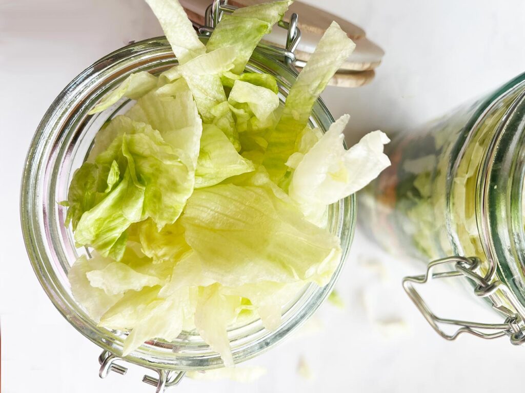 Shredded lettuce added to the top of a salad jar.