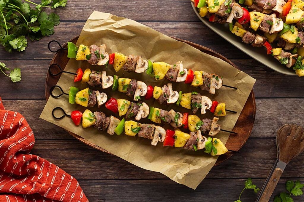 Pork Kabob pieces on skewers laying on a parchment-lined platter.