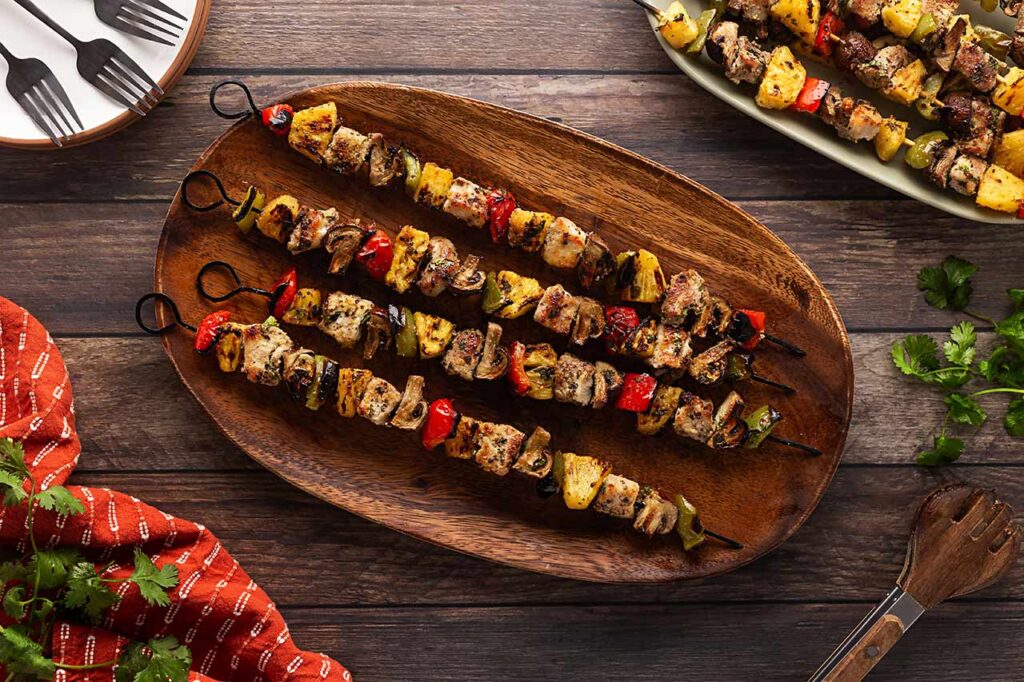 Grilled Pork Kabobs on a wood platter. Overhead focus.