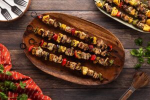 Grilled Pork Kabobs on a wood platter. Overhead focus.