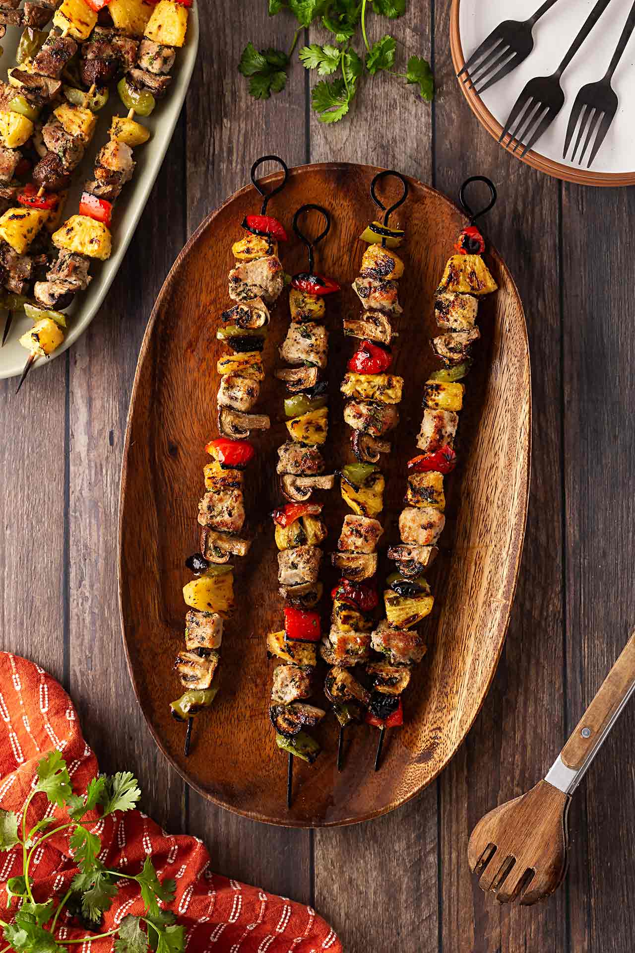 Overhead focus. A wood platter holds four Pork Kabobs.