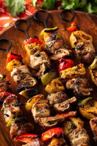 Closeup of four Pork Kabobs on a wood platter.