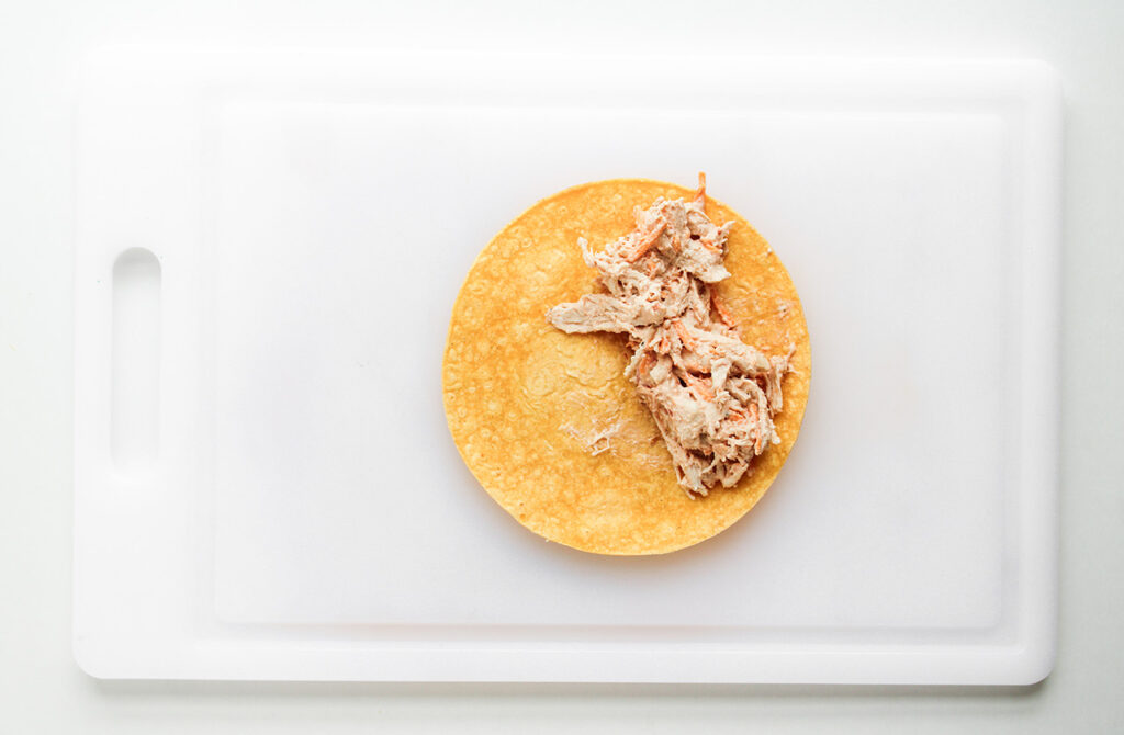 A tortilla laid flat with a big of filling added to one side.
