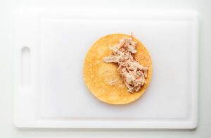A tortilla laid flat with a big of filling added to one side.