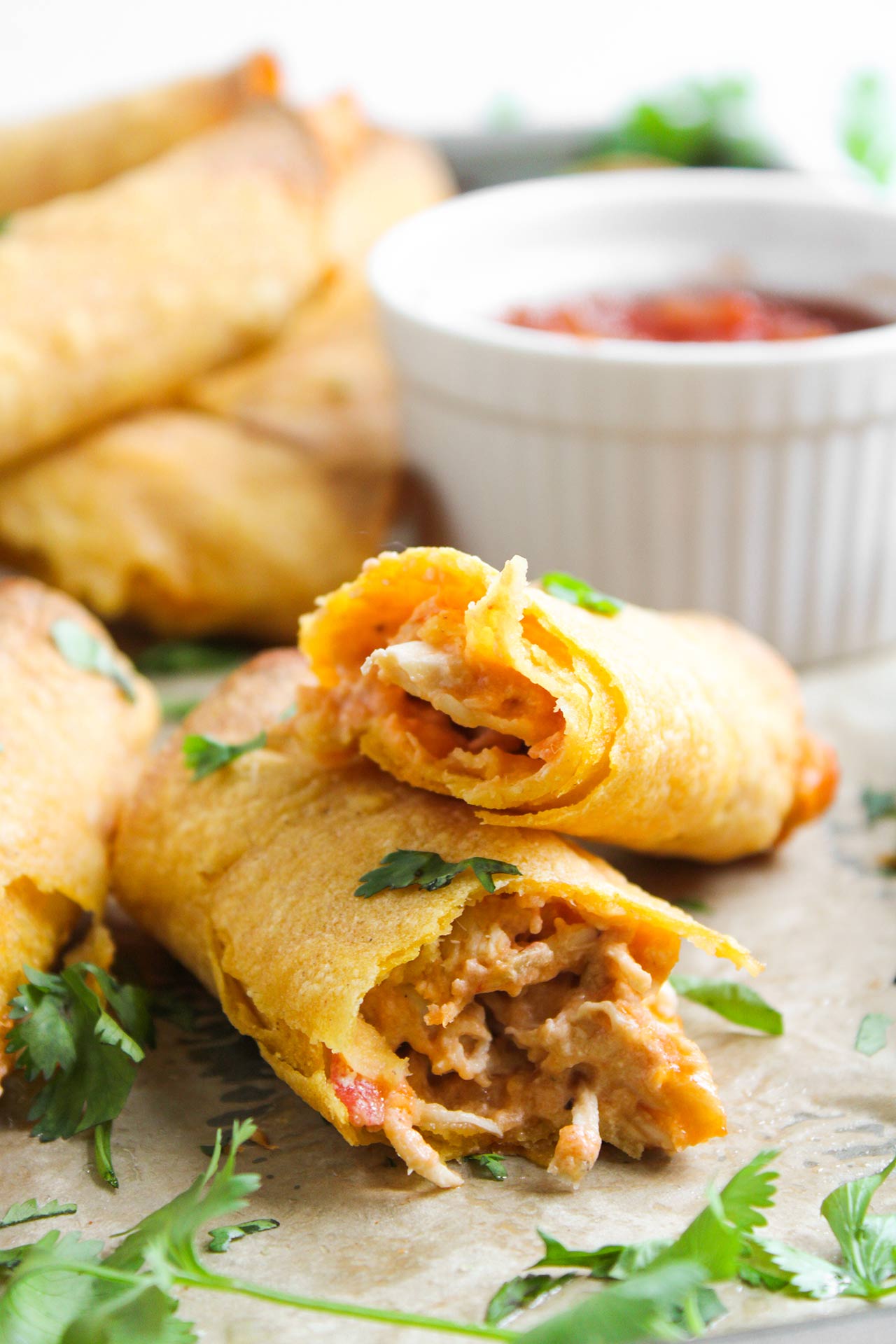 A broken chicken taquito lays on a baking pan.