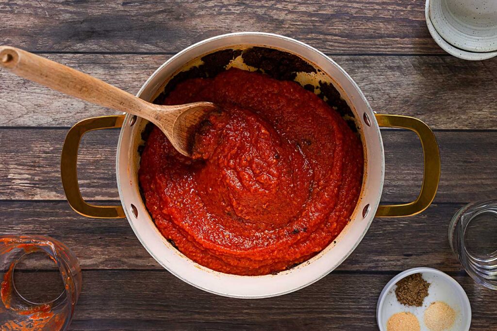 Tomato sauce added to a pot of spices.
