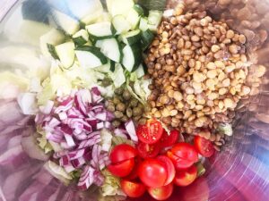 Salad ingredients, unmixed, sitting in a mixing bowl.