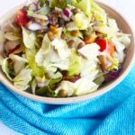 Front view of a bowl of Fusion Lentil Salad with a blue towel in front of it, on a white background.