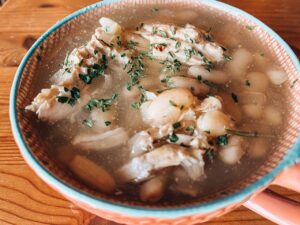 Front view of a bowl of Herb Chicken And White Bean Soup in a mug.