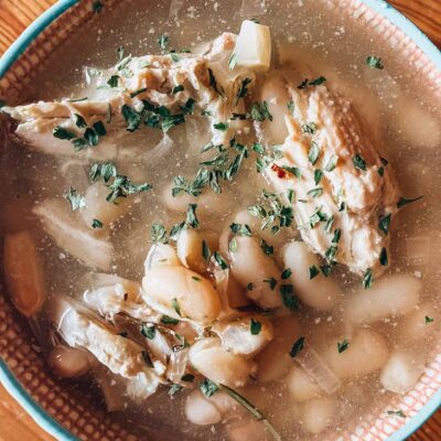 A mug full of Herb Chicken And White Bean Soup. Overhead view.