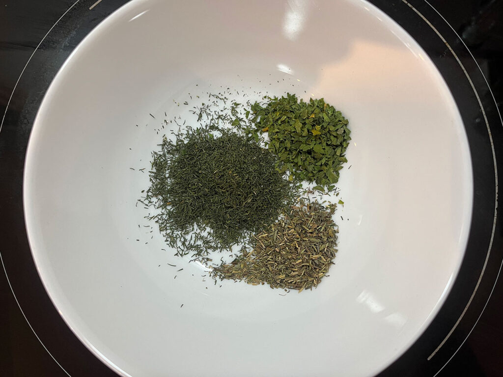Dried herbs in a white bowl.