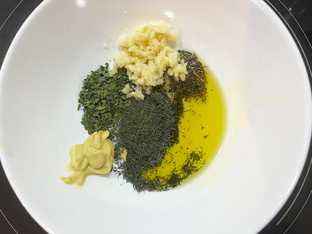 Herb mix ingredients in a white bowl, un-mixed.