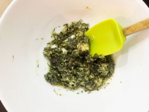 Herb mix in a white mixing bowl with a spatula.