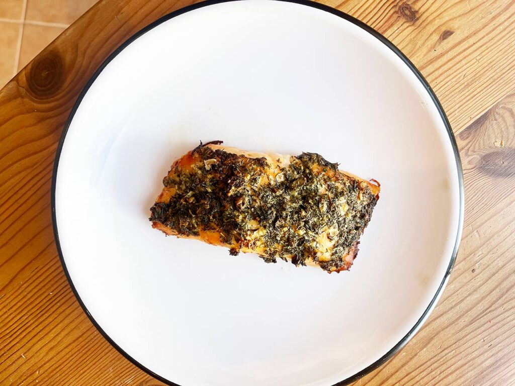 A served Mediterranean Herb-Crusted Salmon fillet on a white plate.