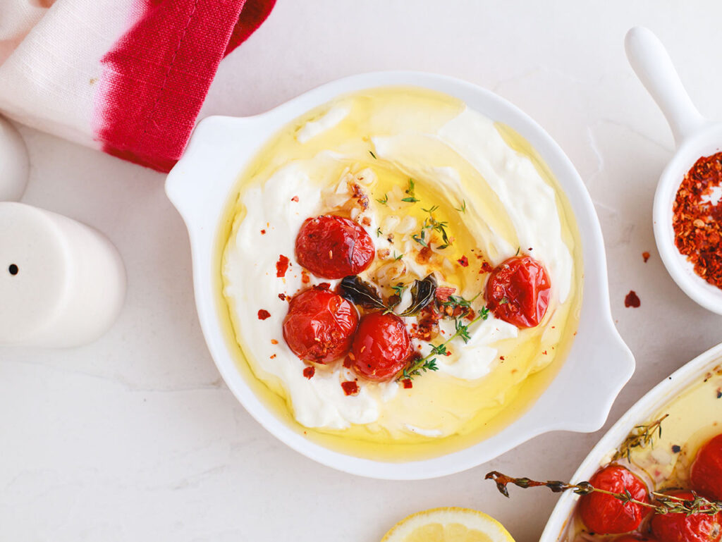 Overhead view of whipped feta in a serving dish with tomato confit on top.