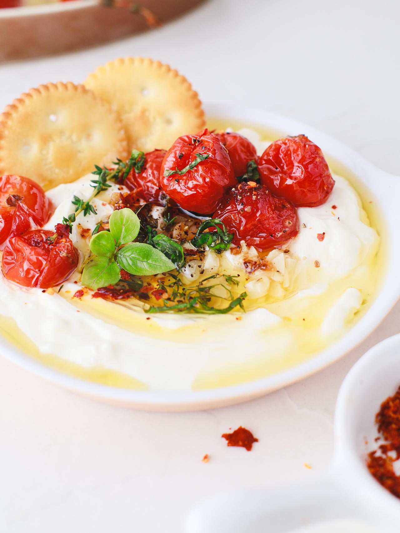 Front view of a white dish filled with Whipped Feta Dip with two cracker sitting in the dip.
