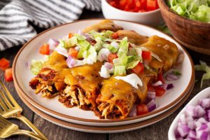 Three chicken enchiladas on a stack of plates.