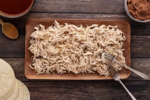 Shredded, cooked chicken on a platter.