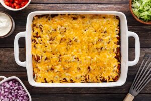 Cheese melted over the top of a casserole dish full of Chicken Enchiladas.