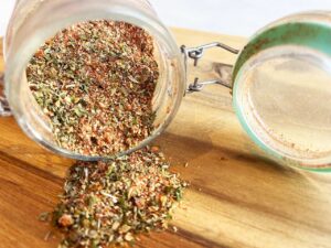 Front view of an open jar on it's side with Copycat Trader Joe's Pizza Seasoning spilling out.