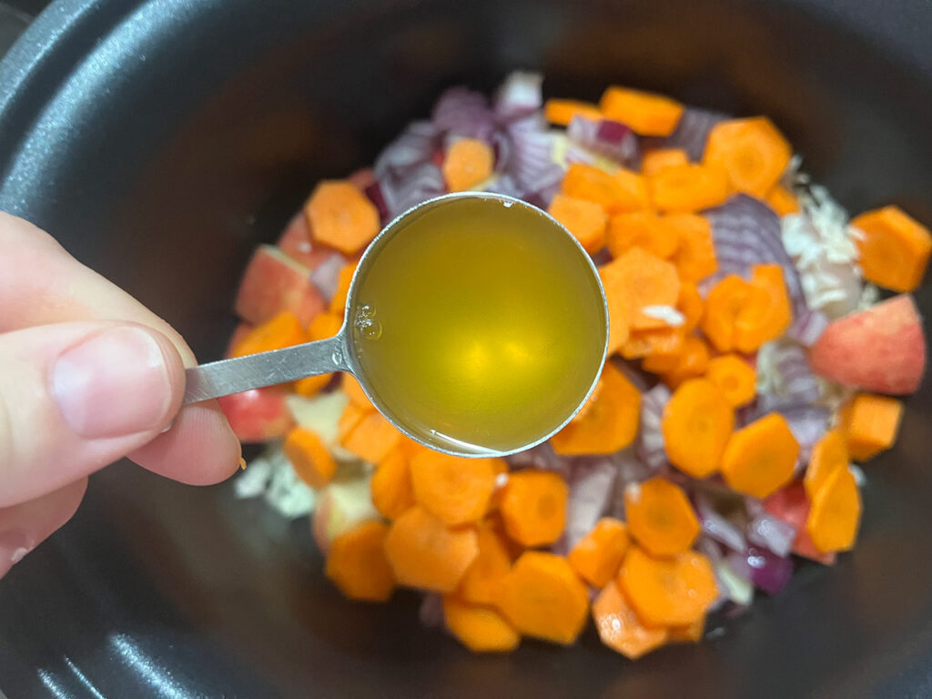 Adding apple cider vinegar to the ingredients in the slow cooker crock.