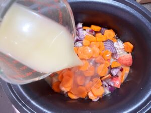 Adding chicken broth to the slow cooker crock.