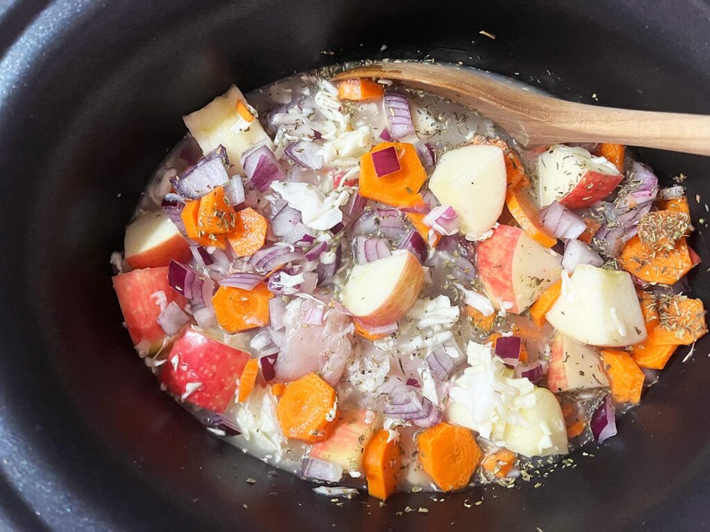 Autumn Slow Cooker Chicken With Apples And Cabbage recipe ingredients mixed together in a slow cooker crock.