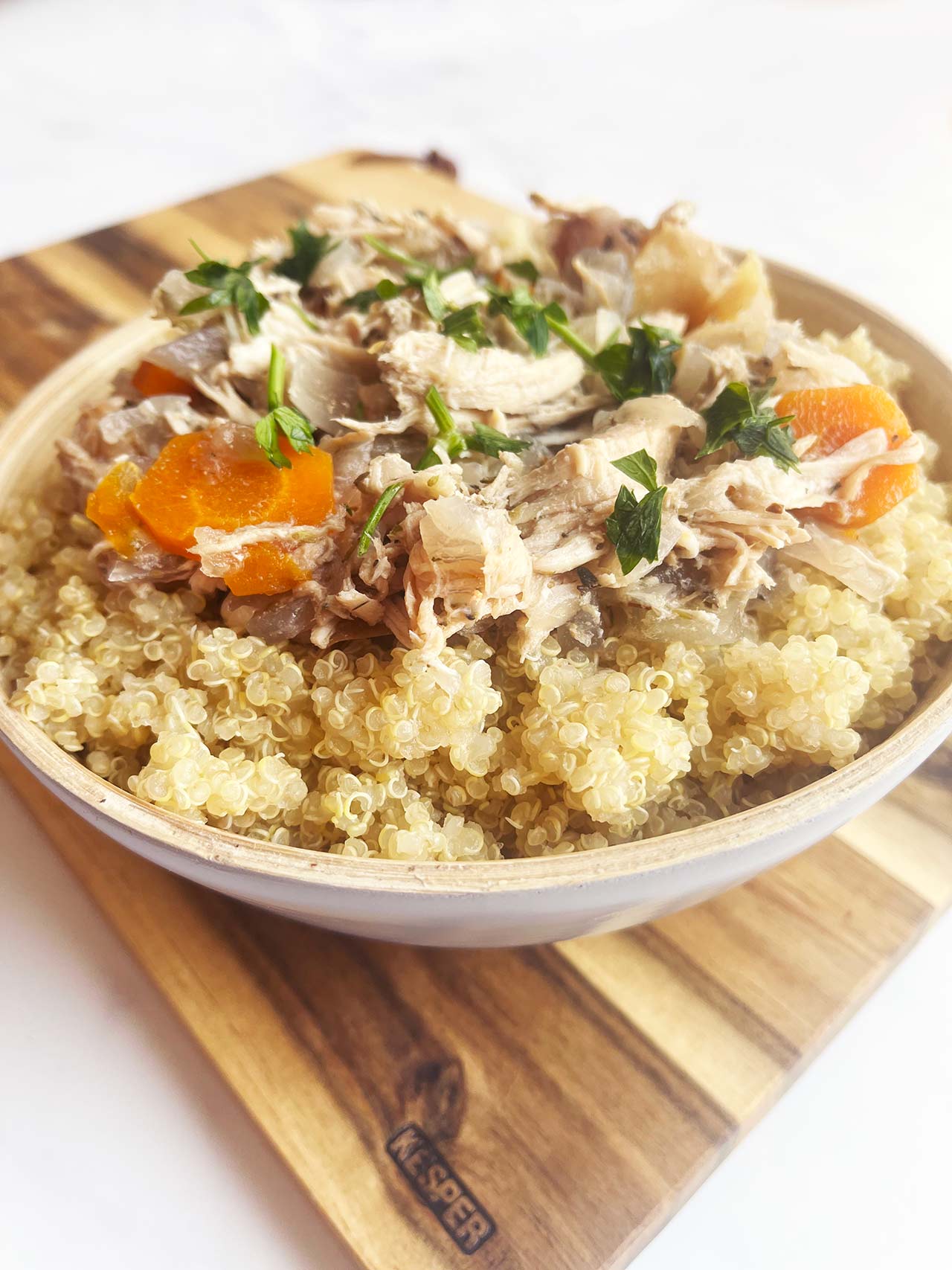 A bowl of Autumn Slow Cooker Chicken With Apples And Cabbage served over quinoa. Front view. A cozy fall slow cooker chicken dinner.