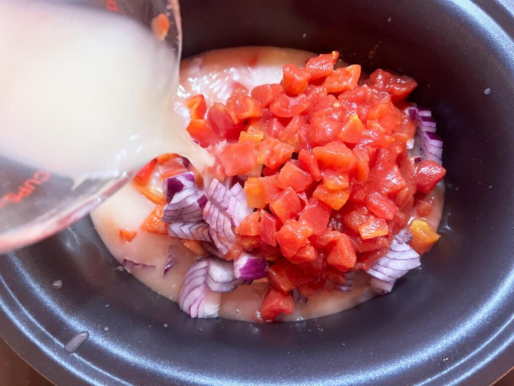 Pouring broth into a slow cooker crock.