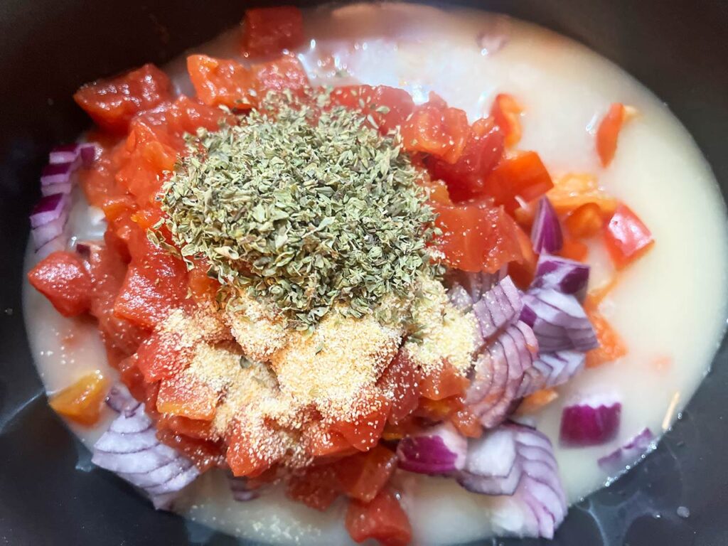 Spices added to ingredients in a slow cooker crock.