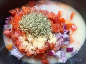 Spices added to ingredients in a slow cooker crock.