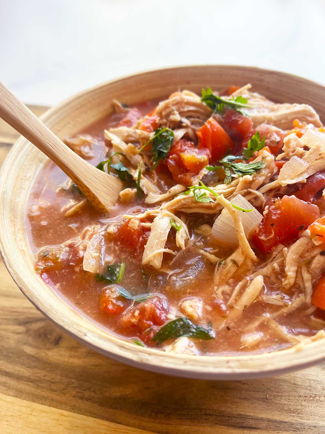 Front view of a bowl filled with Slow Cooker Stuffed Pepper Stew. A wood spoon rests in the bowl.